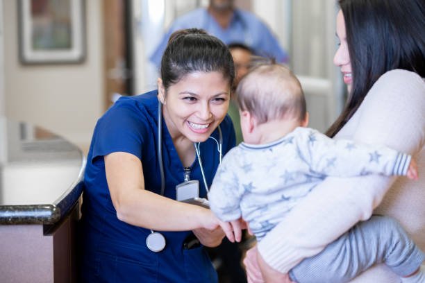 Nurse playing with a baby boy patient after his check-up at a pediatrician's office